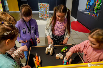 Dzieci bawiące się drewnianymi zabawkami podczas zwiedzania Muzeum Zabawek i Zabawy.