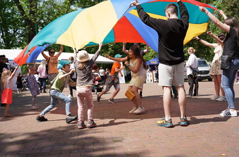 Grupa osób bawiąca się kolorową chustą animacyjną