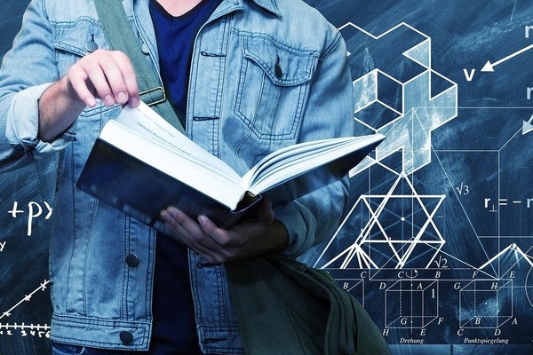 Osoba trzymająca książkę, w tle grafiki z figurami geometrycznymi