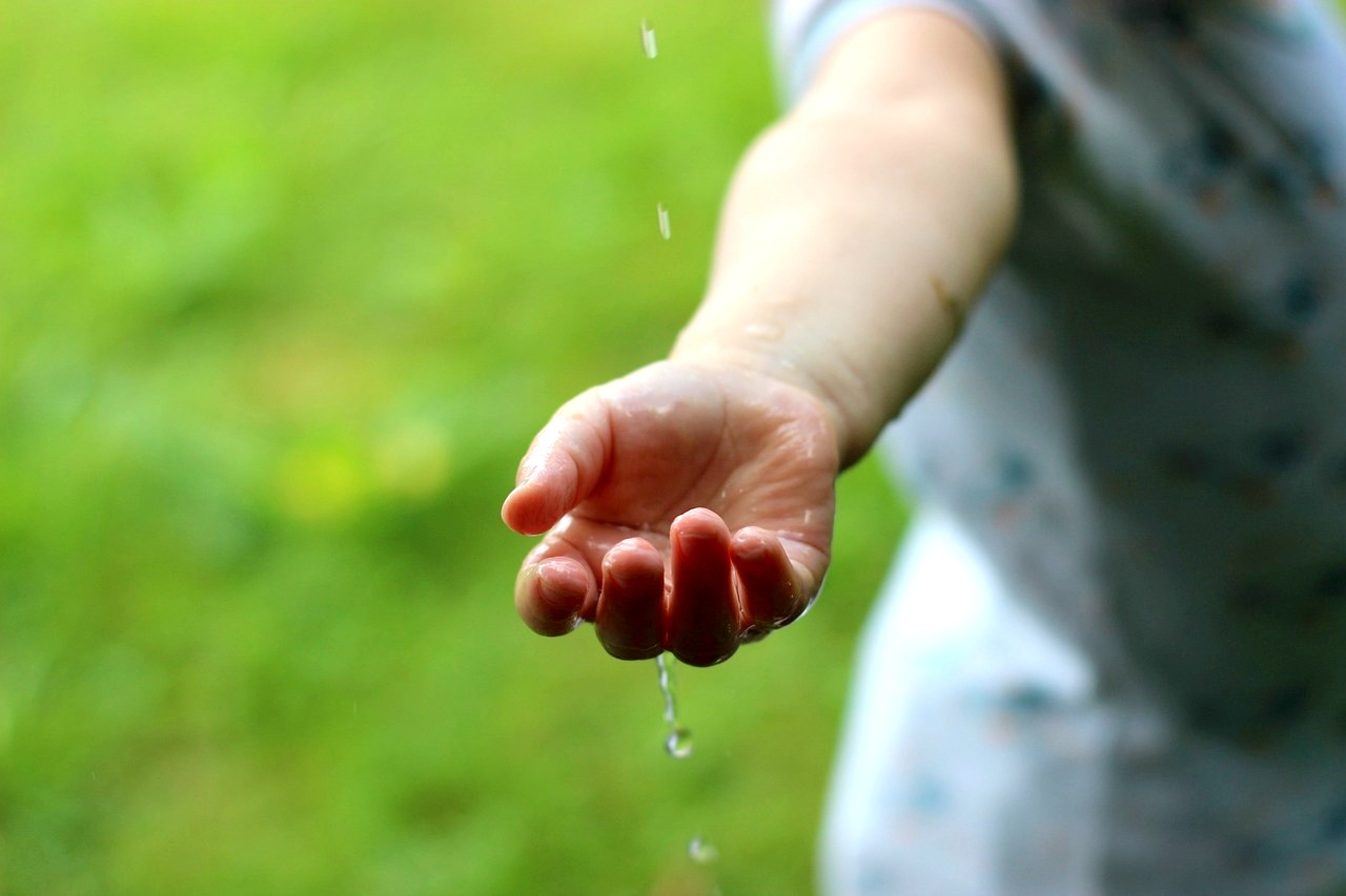 ręka dziecka łapiąca krople deszczu