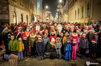 Grupa dzieci i dorosłych na ulicy Sienkiewicza, część osób przebrana jest w kostiumy Świętego Mikołaja