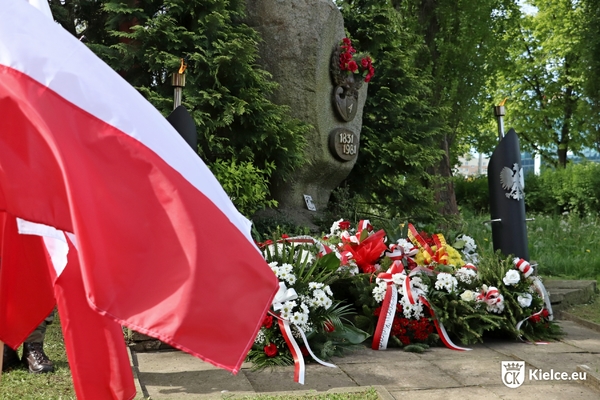 zdjęcie przedstawia pomnik poświęcony uczestnikom Powstania Listopadowego, pod nim wieńce. Po lewej flaga biało-czerwona