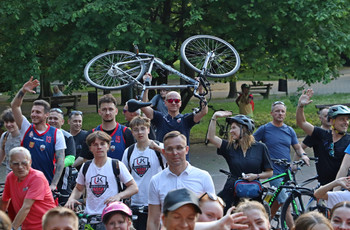 Grupa rowerzystów pozuje do zdjęcia. Jeden trzyma rower nad głową.