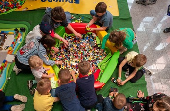 zdjęcie przedstawia dzieci i opiekunów bawiących się klockami LEGO