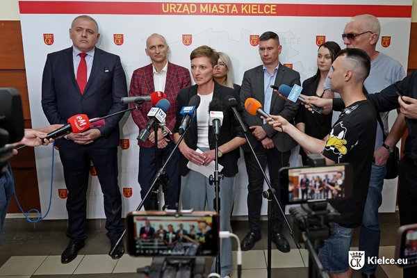 Konferencja prasowa z udziałem prezydentki Kielc Agaty Wojdy (stoi przy mikrofonach) i zaproszonych gości (stoją w tle przy ściance)