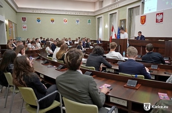 zdjęcie przedstawia młodzież siedzącą na sali sesyjnej w Urzędzie Miasta Kielce; jedna osoba przemawia z mównicy