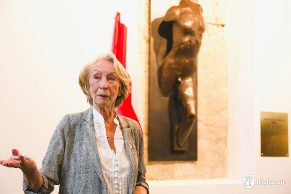 Kobieta stoi obok rzeźby