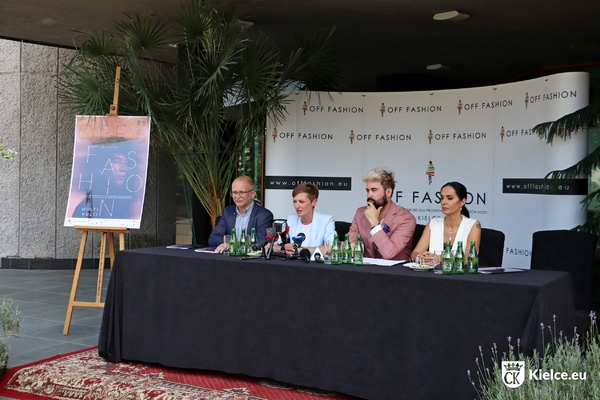 Cztery osoby siedzą przy stole podczas konferencji prasowej. Obok na sztaludze plakat Konkursu OFF Fashion, z tyłu ścianka z logo Konkursu.