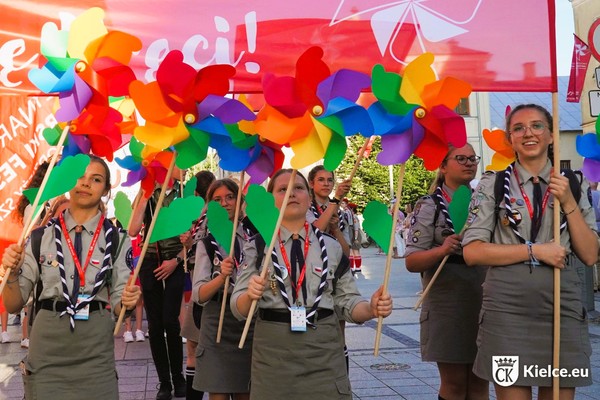 Grupa harcerzy stoi z kolorowymi wiatraczkami w dłoniach