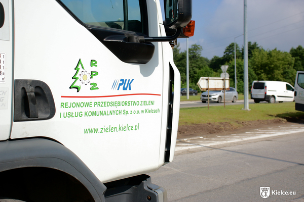 Część białej kabiny pojazdu ciężarowego z umieszczonym na drzwiach logotypem i nazwą Rejonowego Przedsiębiorstwa Zieleni i Usług Komunalnych w Kielcach