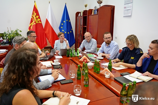 Kilkanaście osób w tym prezydentka Kielc Agata Wojda siedzi przy stole.
