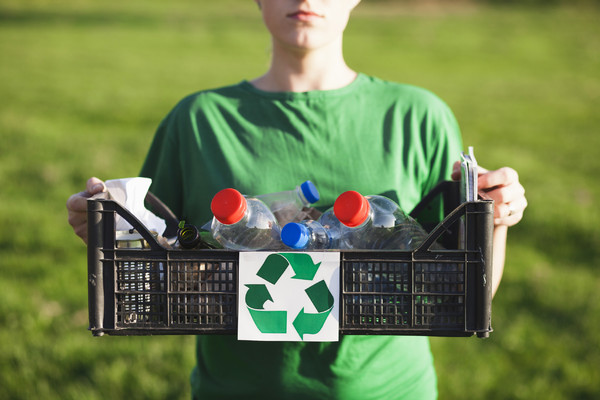 kobieta trzyma plastikową skrzynkę z butelkami do recyklingu