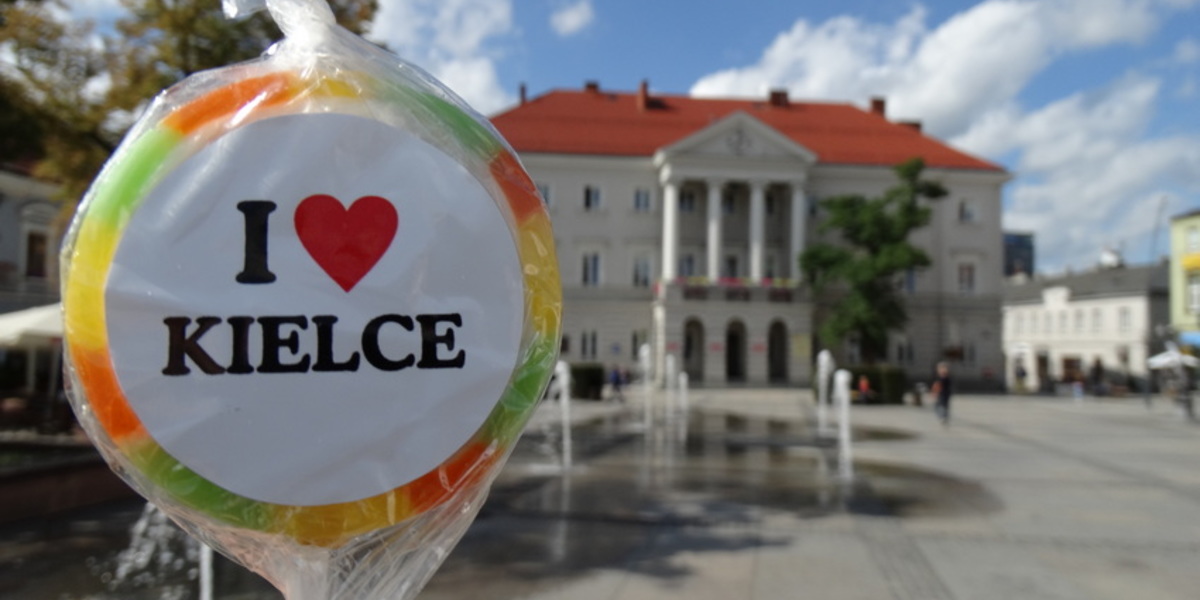 Lizak z napisem I love Kielce na tle kieleckiego Ratusza.